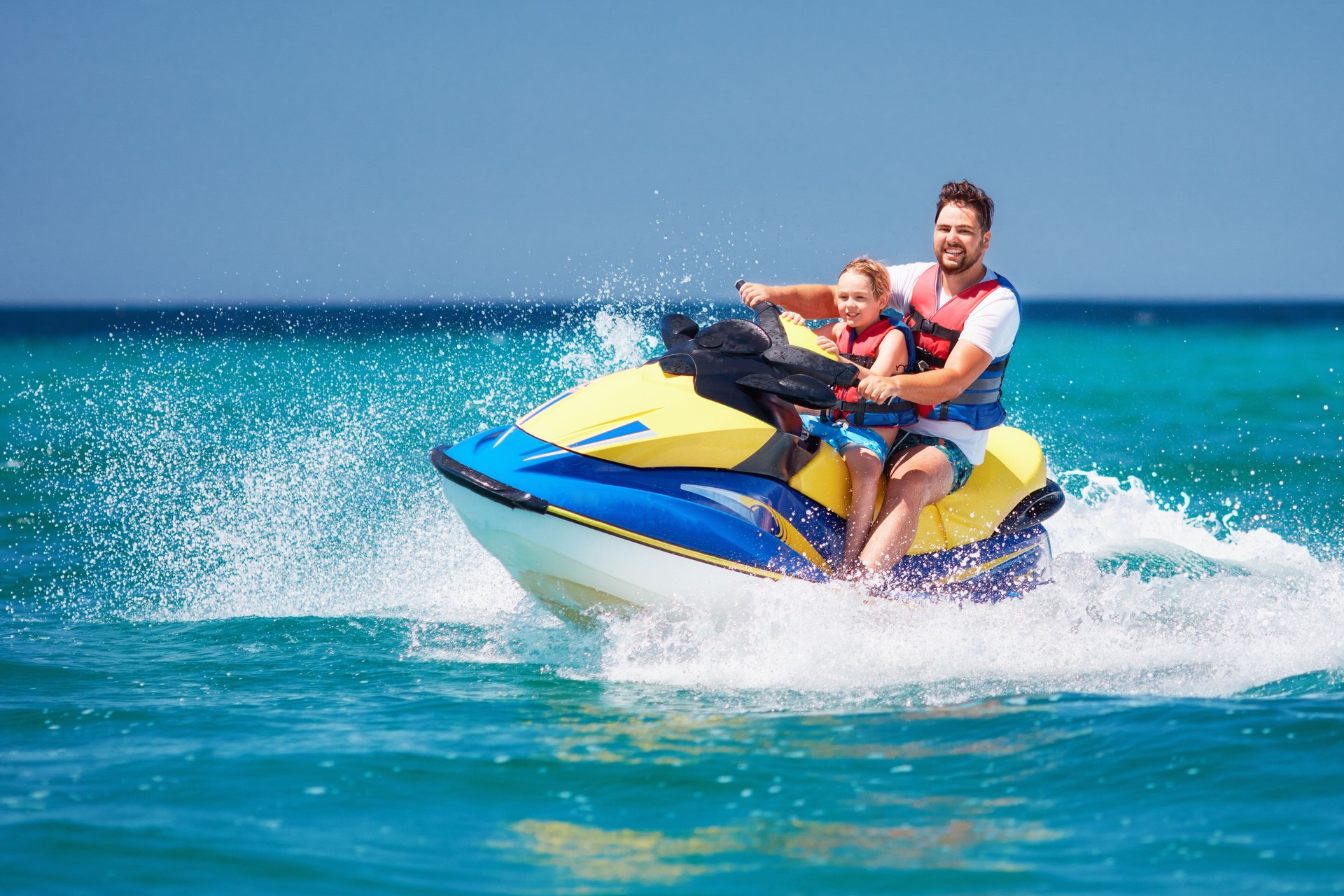 happy, excited family, father and son having fun on jet ski at summer vacation