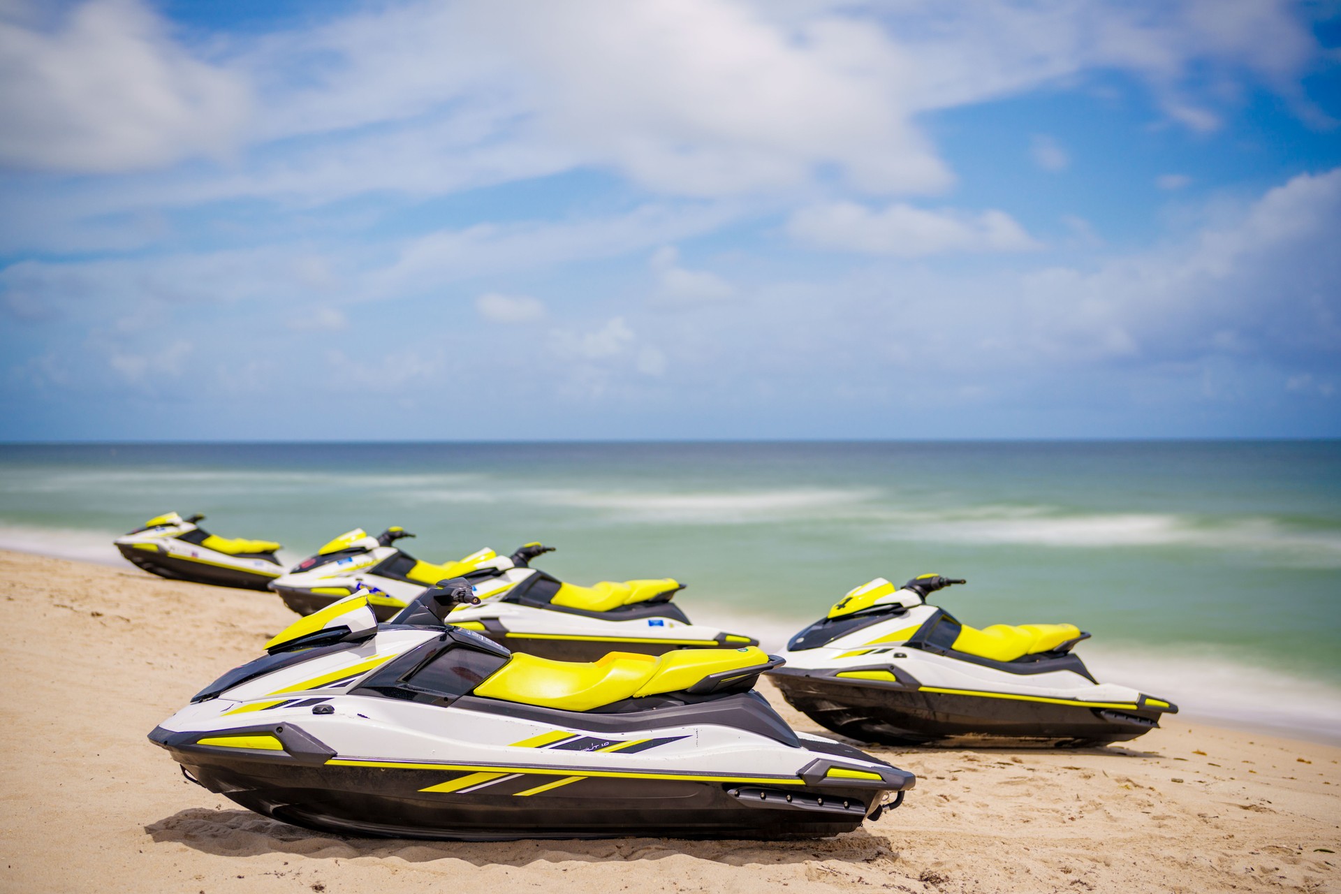 Wave runners on the beach. Summer jet ski sport rentals. Long exposure with motion blur in water and clouds